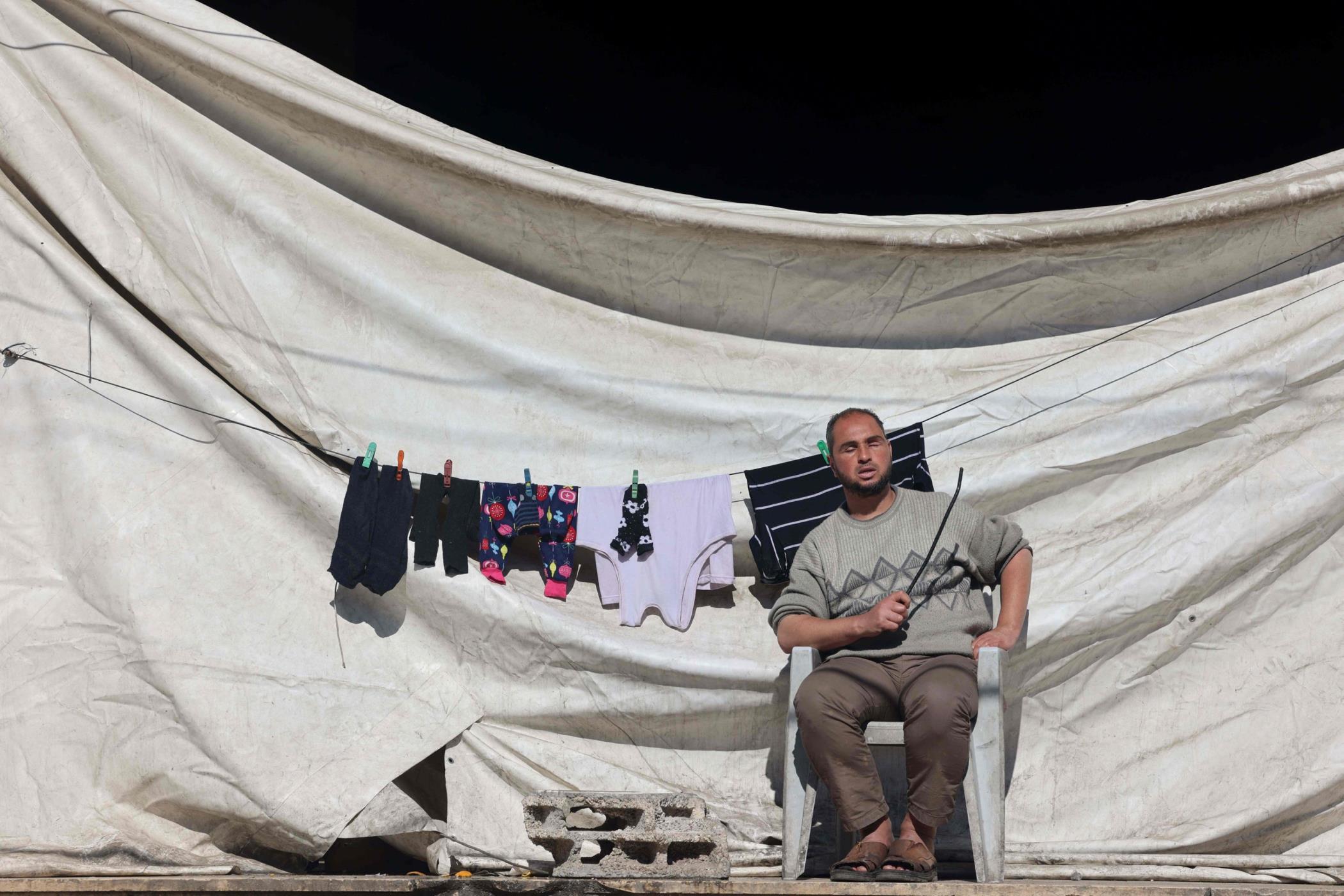 A blind Palestinian man sits on a chair in the sun next to a clothesline in Rafah, Gaza, Palestine, Feb. 11, 2024. (AFP Photo)