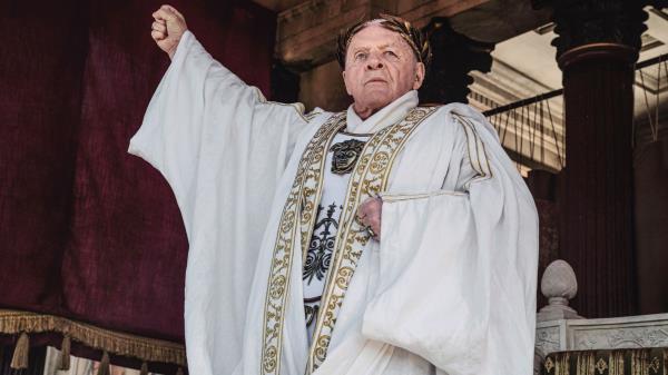 Anthony Hopkins raising his fist while wearing white robes in Those a<em></em>bout to Die