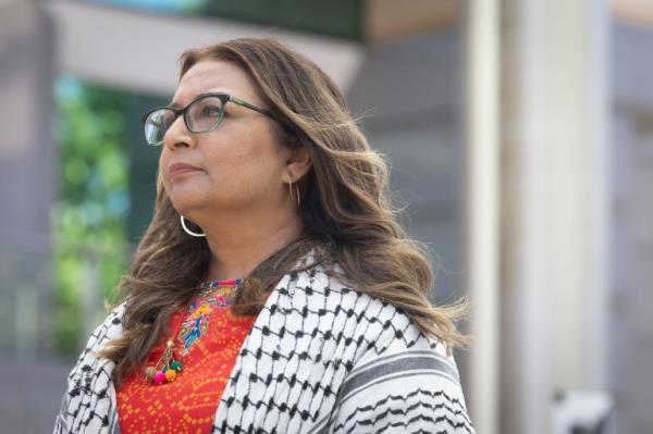 A woman looks into the distance she is wearing a black and white scarf