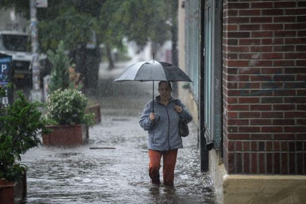 A woman holding an umbrella walks through through floodwater in Brooklyn, New York on September 29, 2023. (Photo by Ed Jo<em></em>nES / AFP) (Photo by ED JONES/AFP via Getty Images)