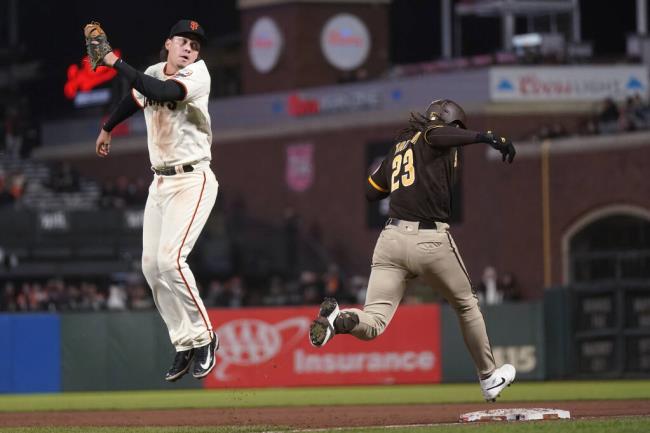 The San Diego Padres’ Fernando Tatis Jr. reaches first ba<em></em>se as Giants first ba<em></em>seman Wilmer Flores looks for the ball on a throwing error by shortstop Marco Luciano during the 10th inning in San Francisco, Wednesday, Sept. 27, 2023. Tatis advanced to second. (Jeff Chiu / ASSOCIATED PRESS)